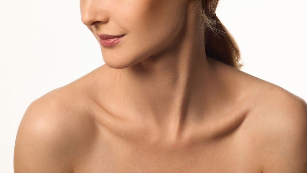 Cropped image of female face, neck and bare shoulders, young woman with glowing skin, emphasizing neck and jawline beauty
