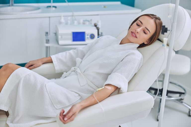 Redheaded beautiful female resting and getting IV infusion in spa salon