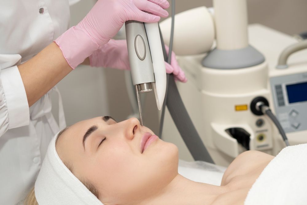 Doctor cosmetologist makes a laser dermal rejuvenation procedure to a patient.