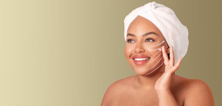 A woman relaxed and smiling while applying a facial massage technique at home