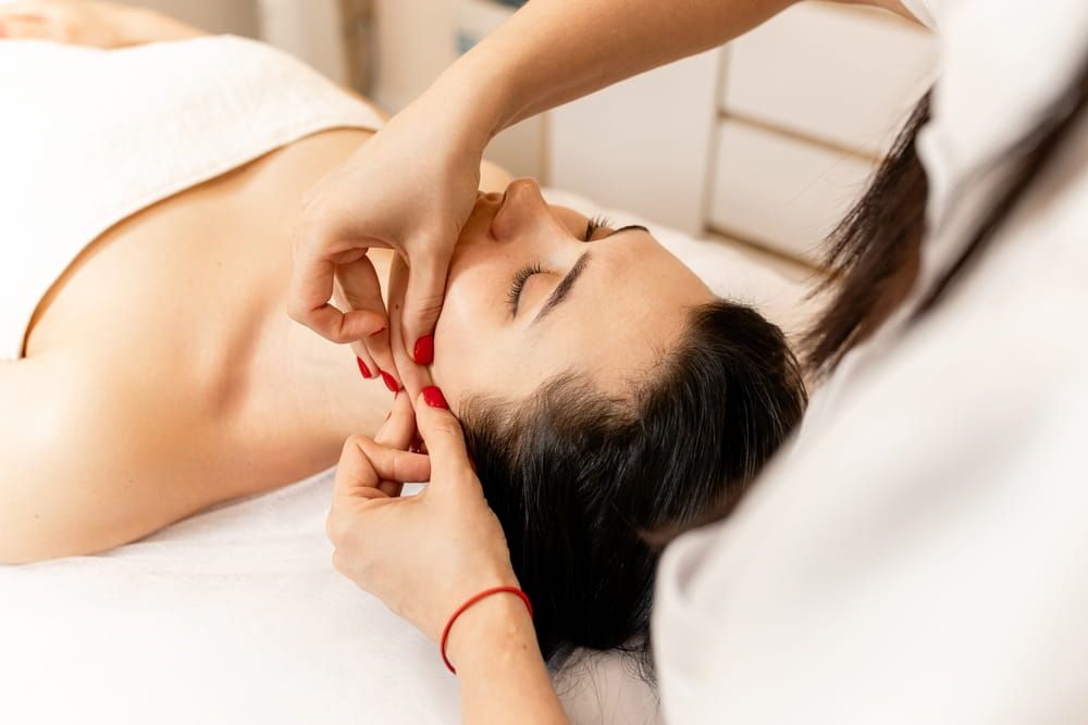 Face Fitness. Beautiful woman receiving face lifting massage in beauty salon.