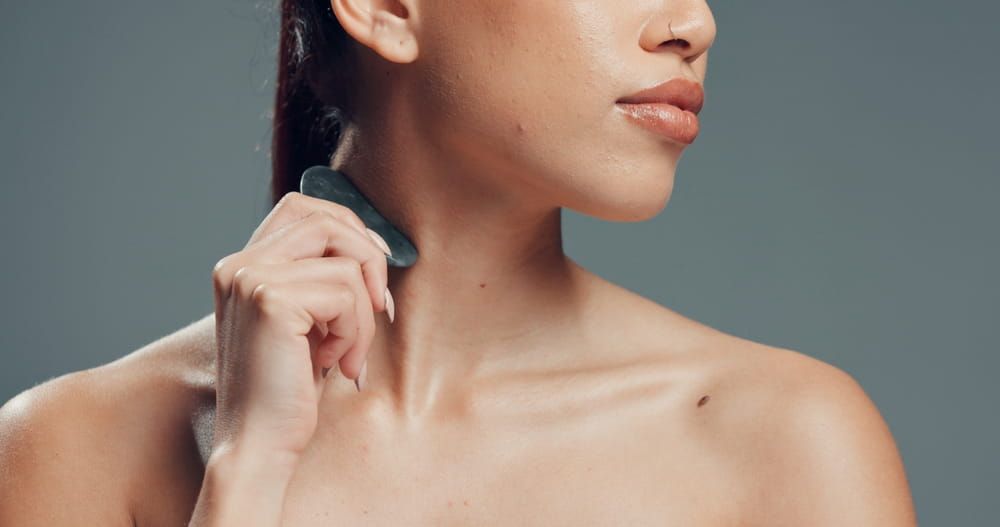 Skincare, neck or woman in studio with gua sha, facial benefits or massage in self care.