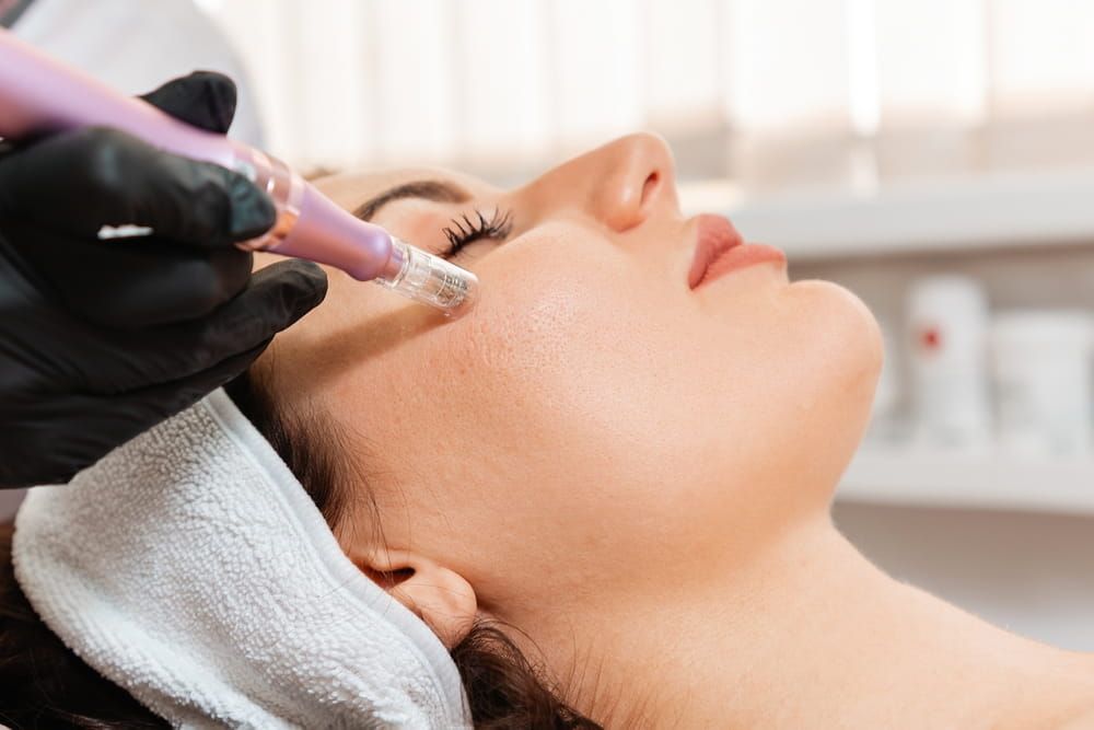 Salon cosmetology. Cosmetologist in protective gloves does procedure of apparatus fractional mesotherapy of woman's face.