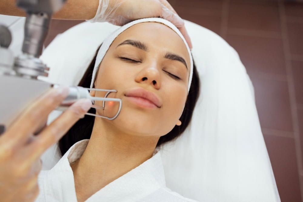 Closeup of the face of young woman undergoing laser resurfacing and peeling procedure in spa salon.