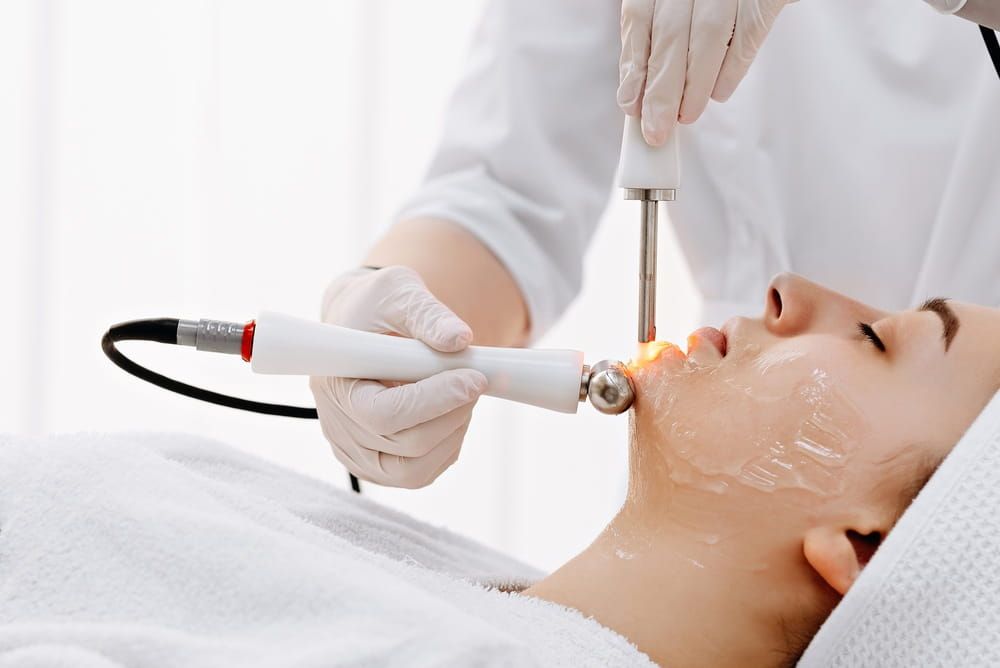 A relaxed woman undergoes a professional laser and radiofrequency facial treatment at a medical spa