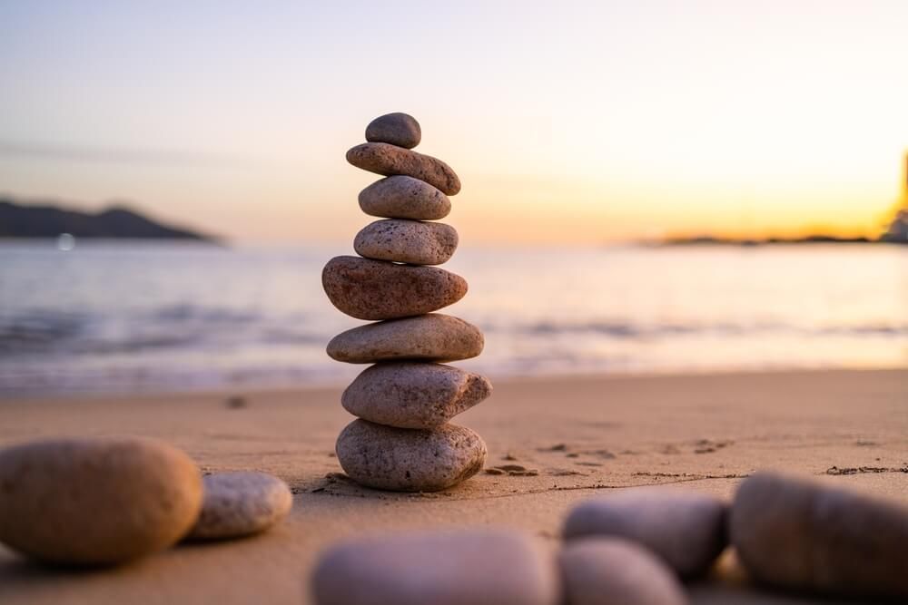 Balance pebble stone in the sand beach at sunset