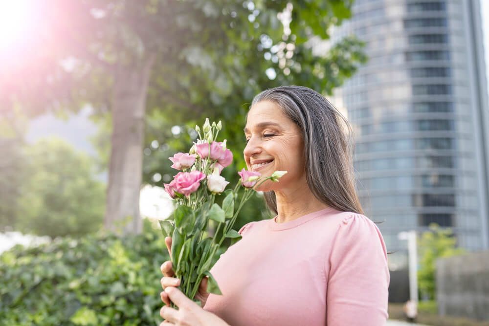 happy mature woman with flowers in a park, mature woman with flowers