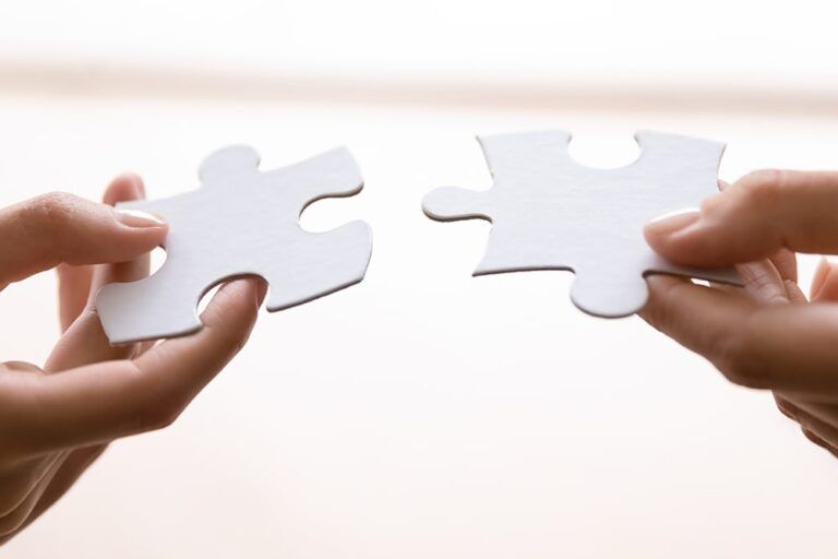 Human connecting two pieces of puzzle. Woman joining jigsaw parts.