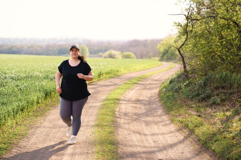 Young overweight woman running in nature.