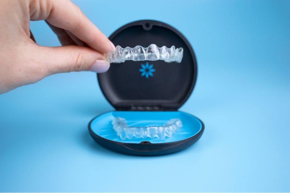 Hands holding invisalign transparent retainers with a box on