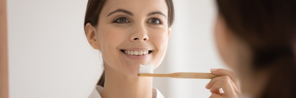 woman holding toothbrush infront of the mirror