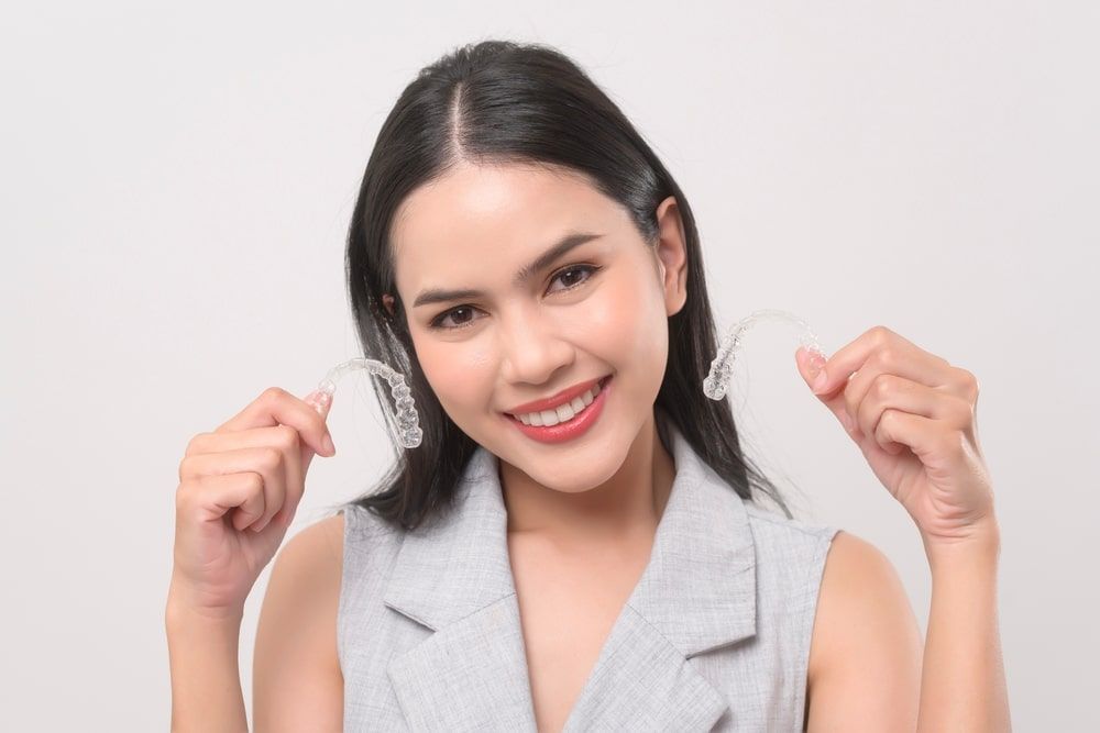 a woman holding an invisalign tray