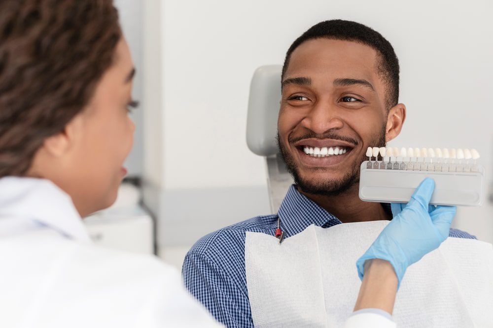 Cheerful patient and female dentist choosing filling shade