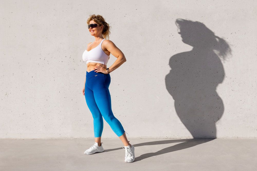 Fit woman standing with her old body left in shadow