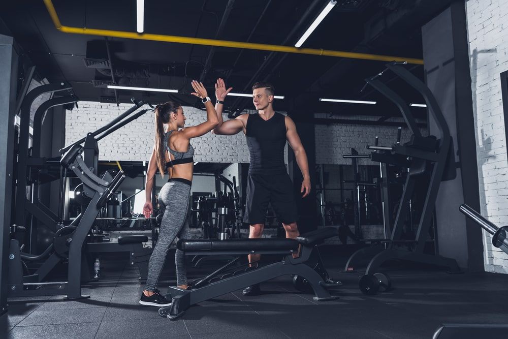 Sportive couple giving high five to each other in gym