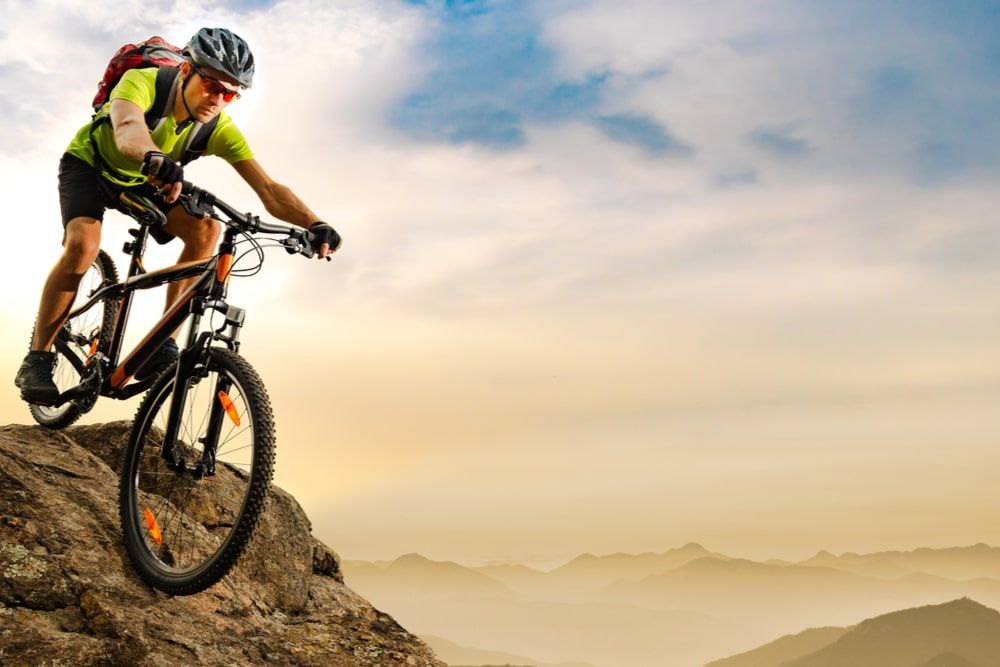 Cyclist Riding the Bike Down the Rock at Sunrise
