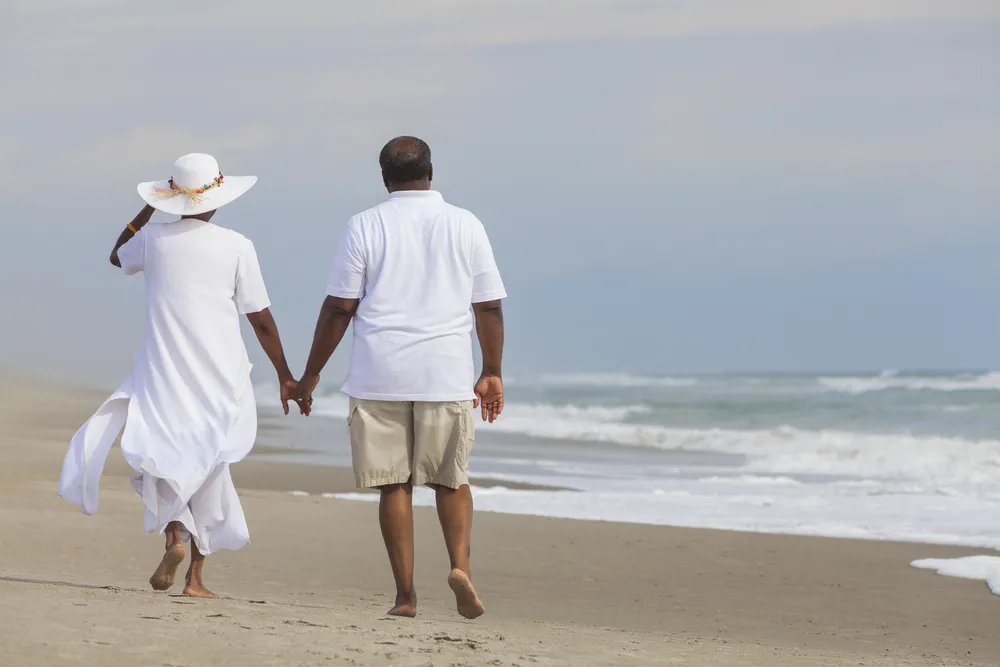 Older couple walking hand in hand along the beach