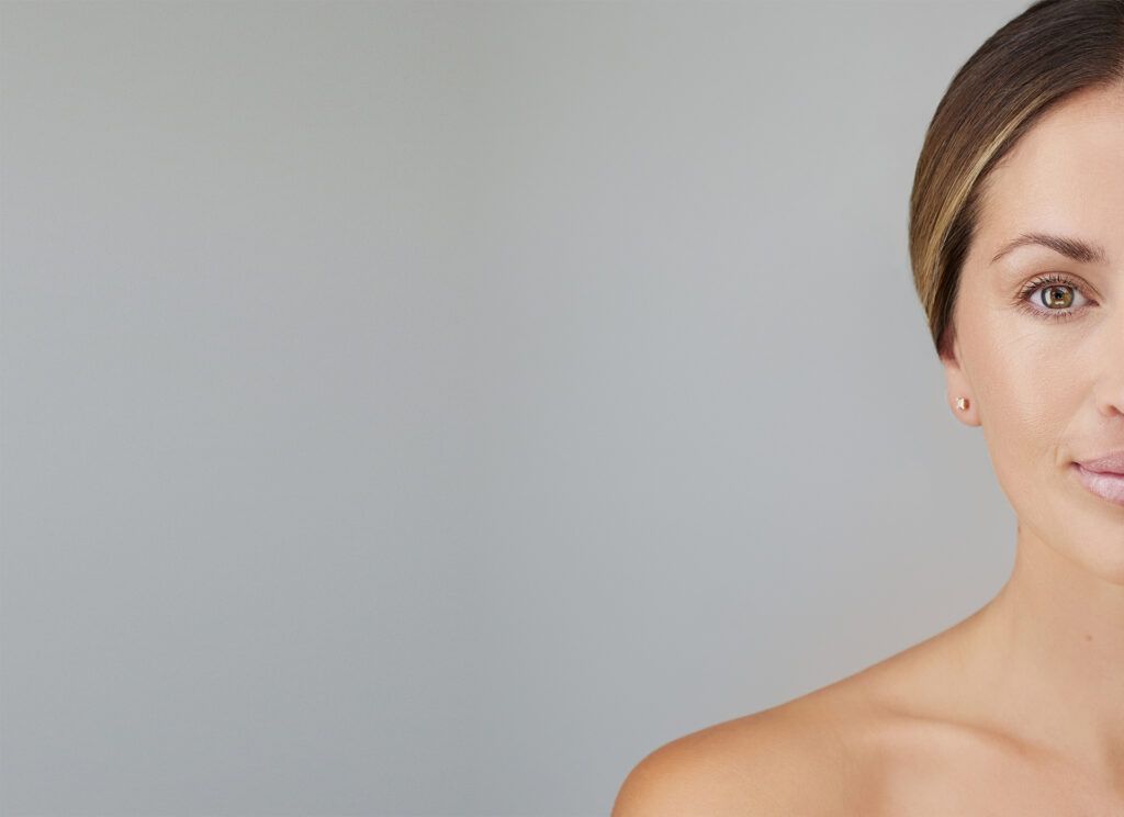 cropped view of young woman with bare shoulders isolated on grey