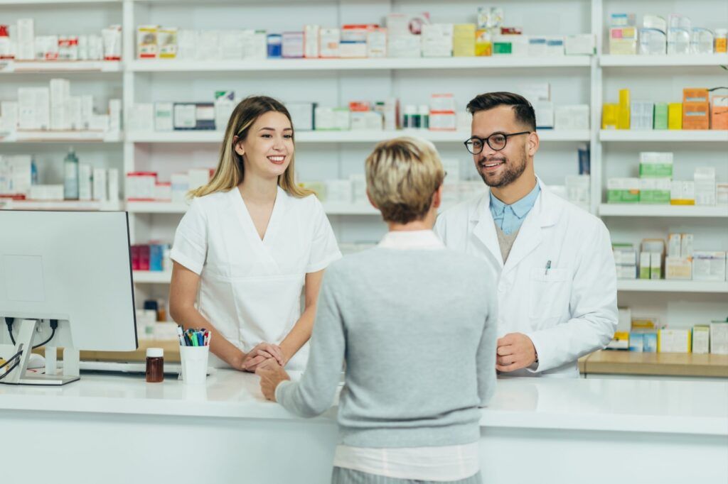 Two pharmacist giving prescription medications to senior female