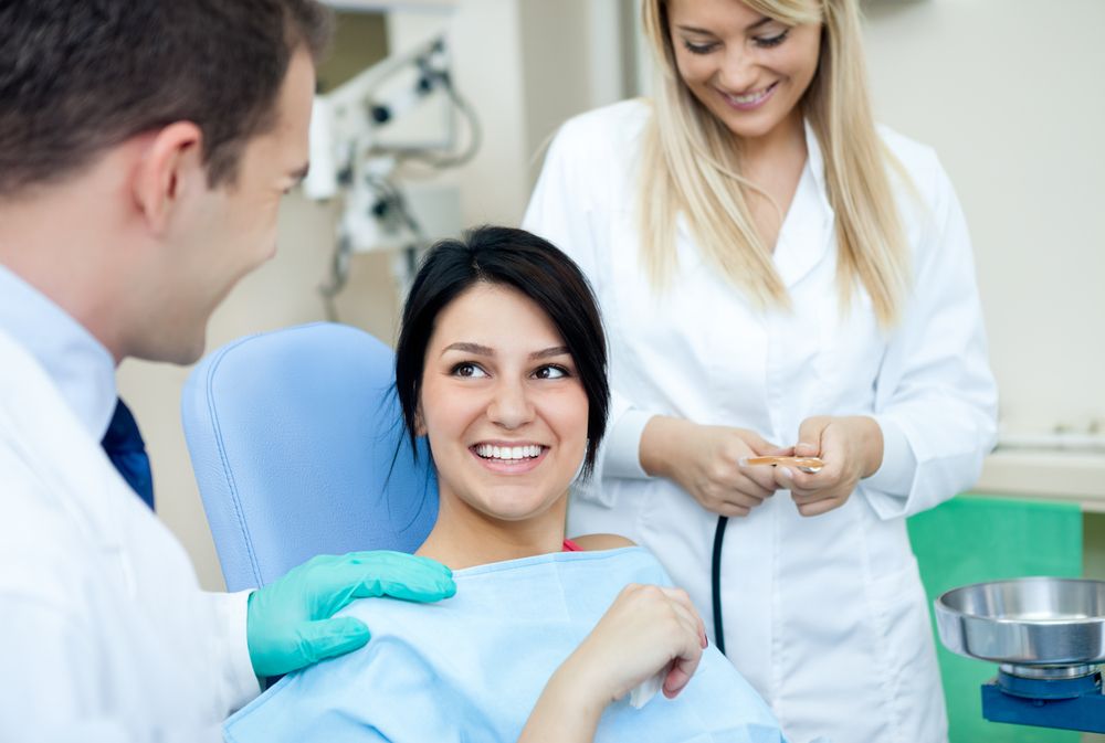 Doctor, his assistant and female patient in dental practice