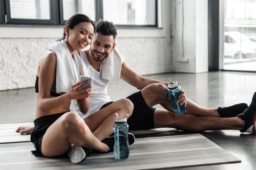 happy sporty young couple resting on yoga mats