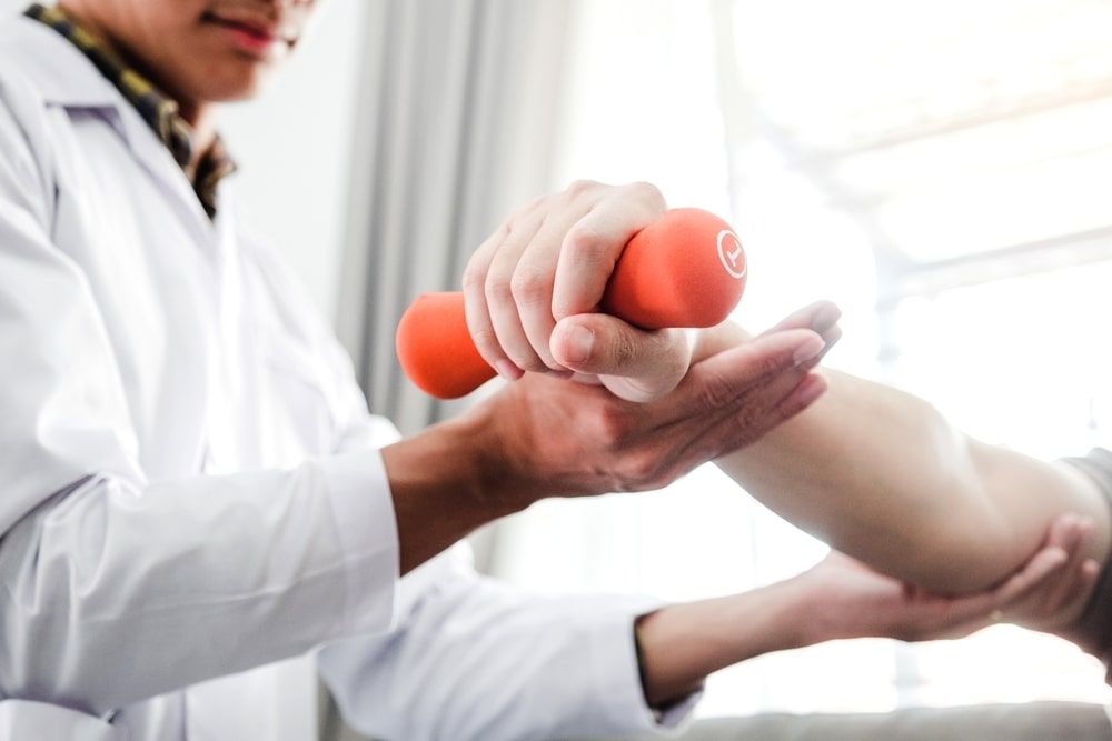 Physiotherapist man giving exercise with dumbbell