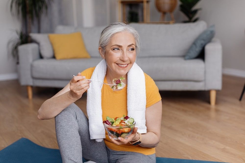 Happy senior woman eating fresh vegetable salad