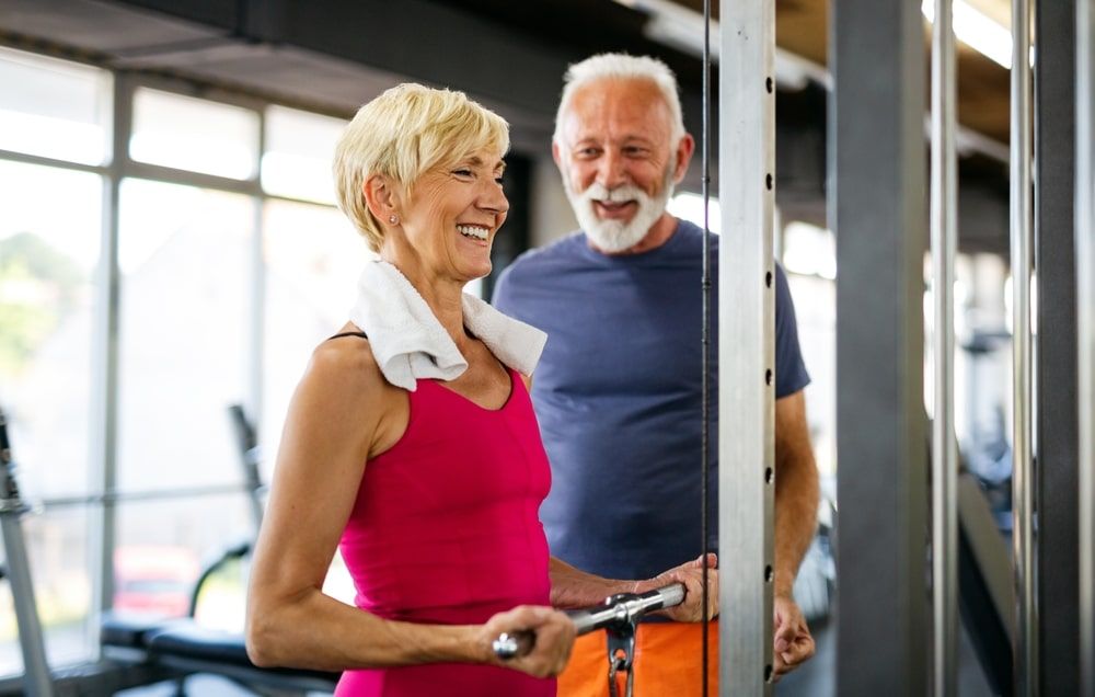 Senior fit man and woman doing exercises in gym to stay healthy