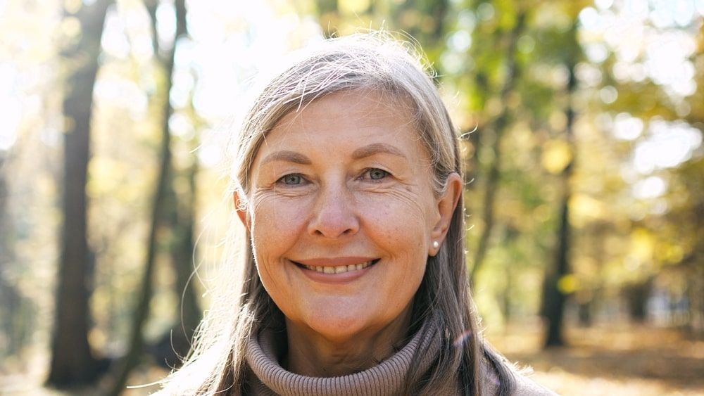 beautiful senior gray-haired woman standing in park in autumn