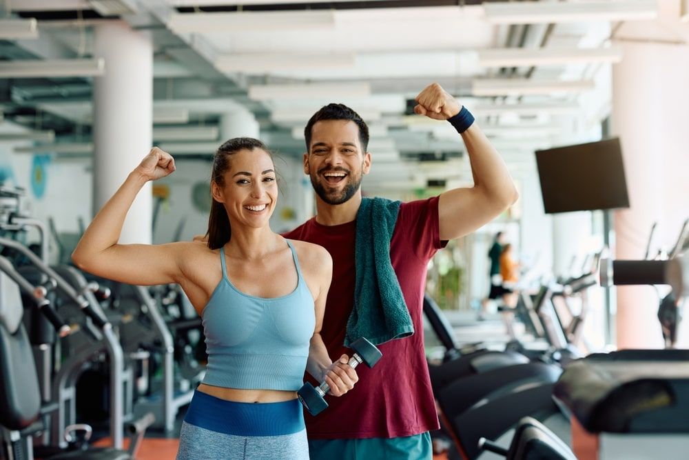 Happy couple flexing their muscles after working out