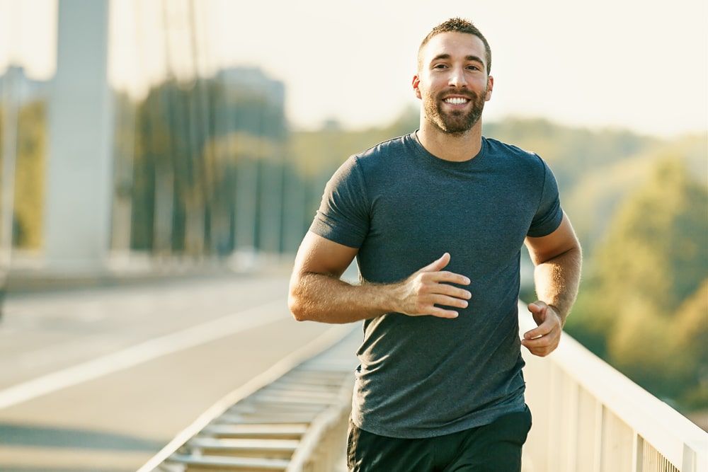 Handsome young man running across the bridge