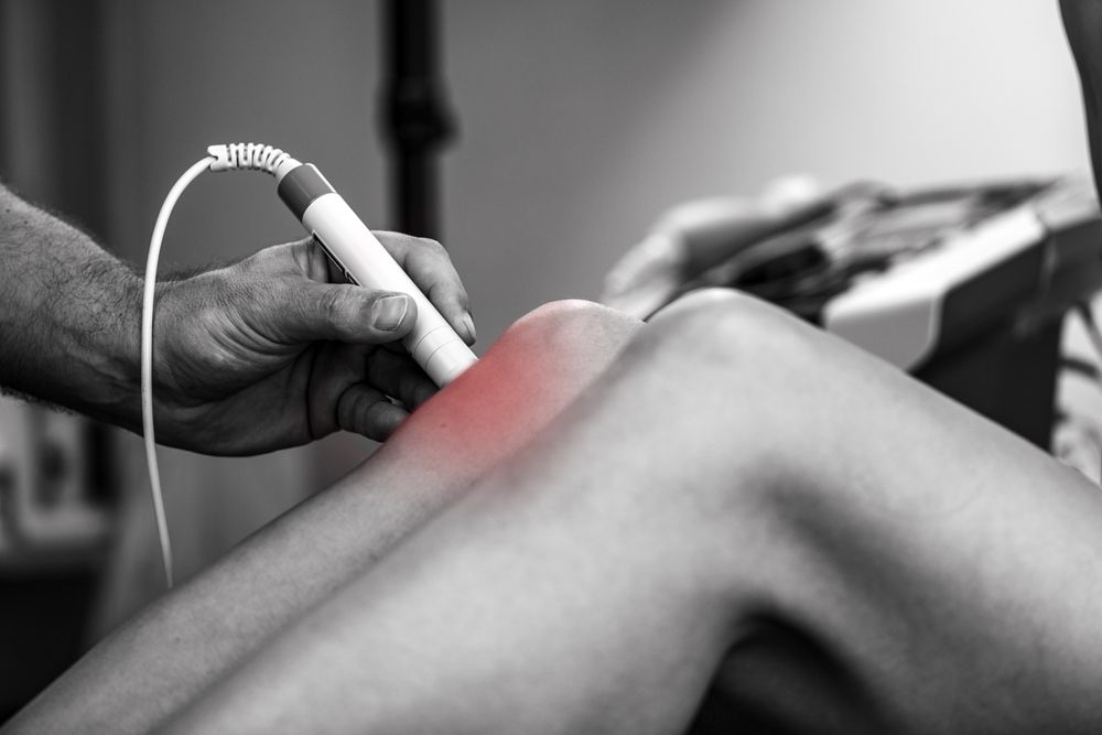 laser therapy on a patient's knee to reduce pain and inflammation, promoting faster recovery and improved mobility through targeted light treatment