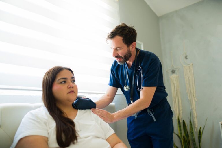 doctor visiting a recovering patient at her home, applying a warm compress to her shoulder after surgery