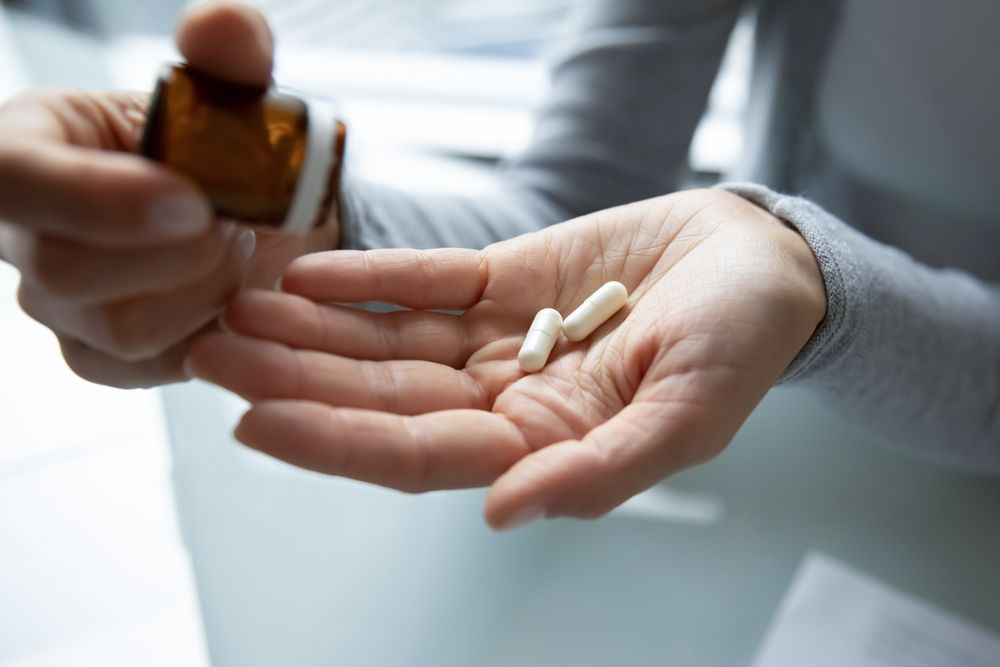 Close up young woman holding pills and bottle with medicine
