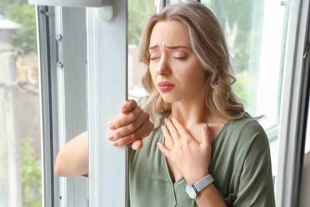 Young woman having panic attack near window