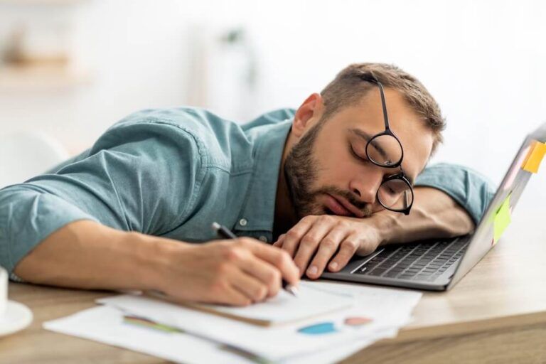 Exhausted millennial man sleeping on his office desk
