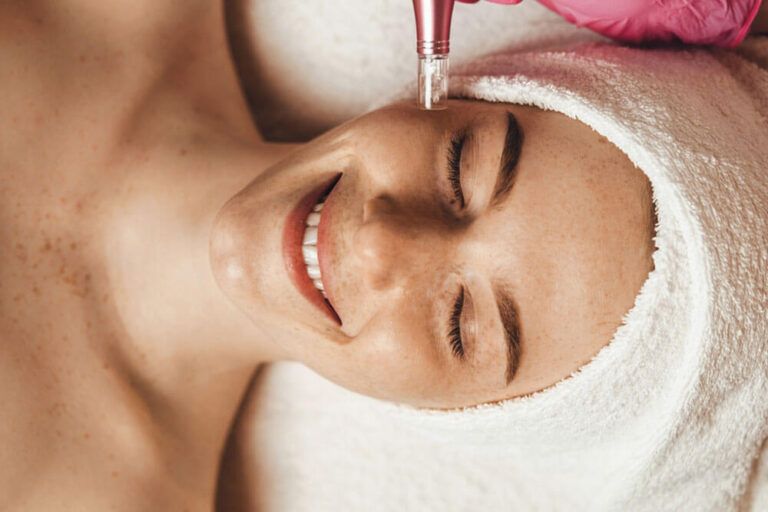 Attractive female patient smiling while receiving face oxygen peeling at spa salon