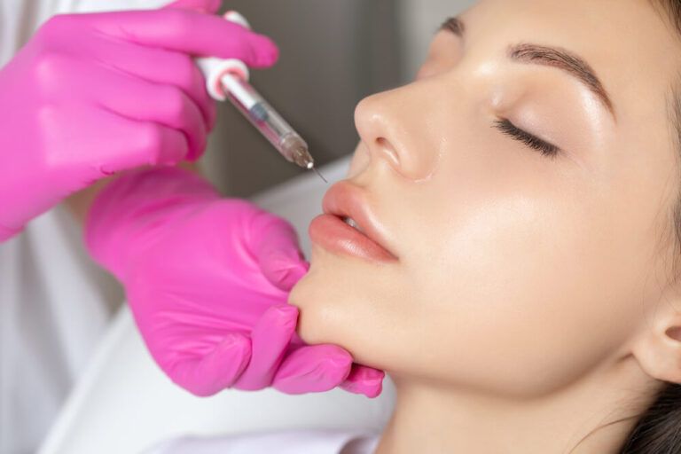 Cosmetologist does injections for lips augmentation of a beautiful woman