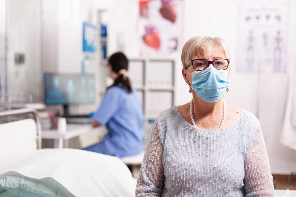 Sick elderly patient woman waiting diagnosis from doctor during treatment wearing face mask
