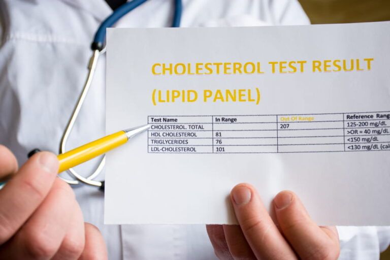 Doctor indicates patient or colleague on cholesterol test result or lipid panel, standing in white medical coat