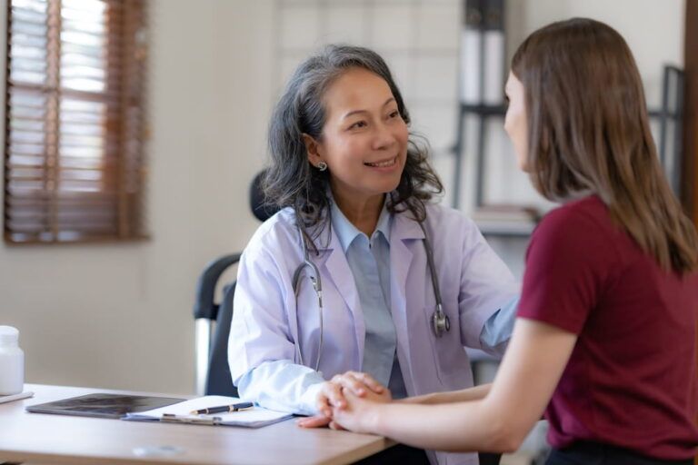 Smiling Asian female doctor having a positive interaction with a female patient.