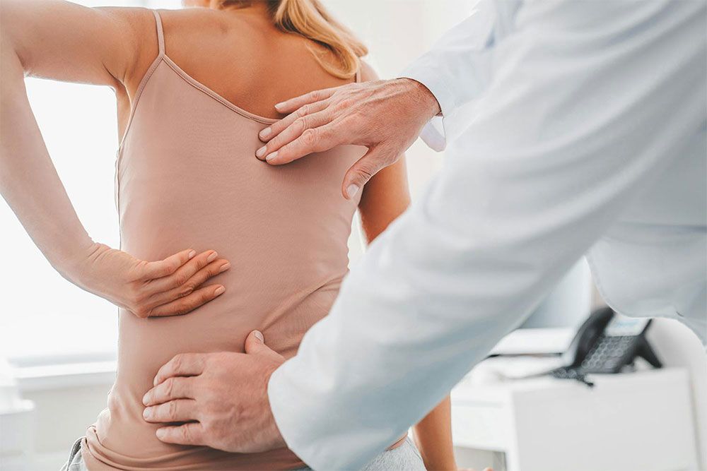 male orthopedist examining patient's back in clinic