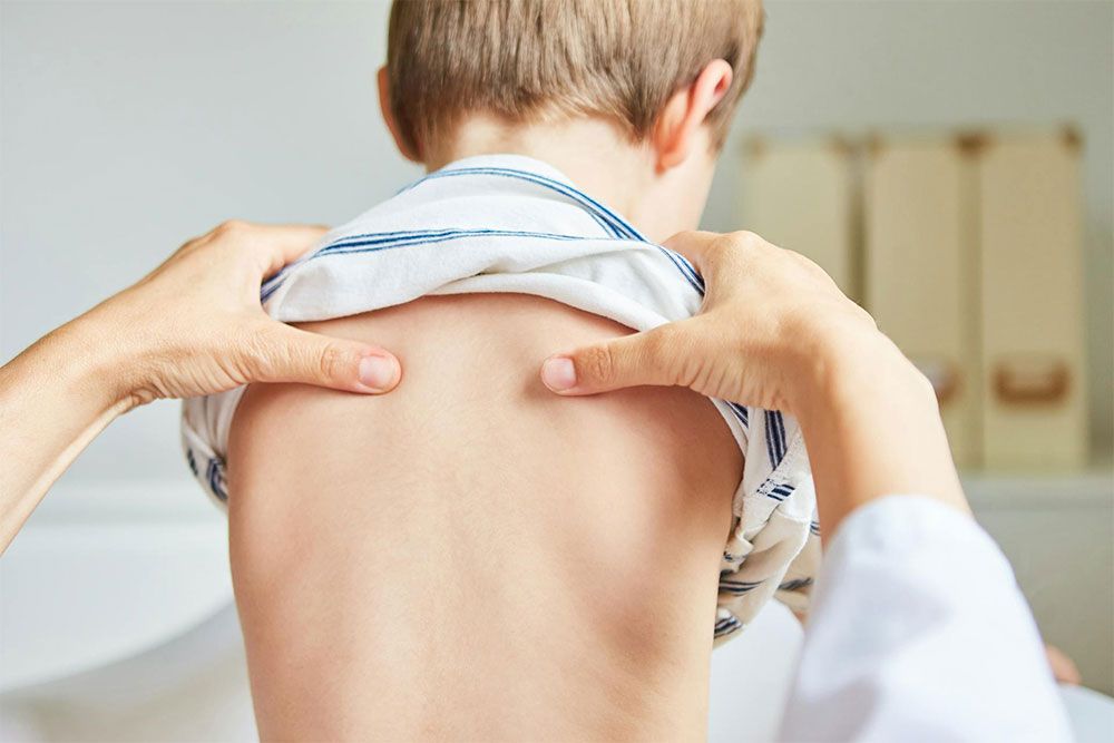 Chiropractor does acupressure on back of child with back pain