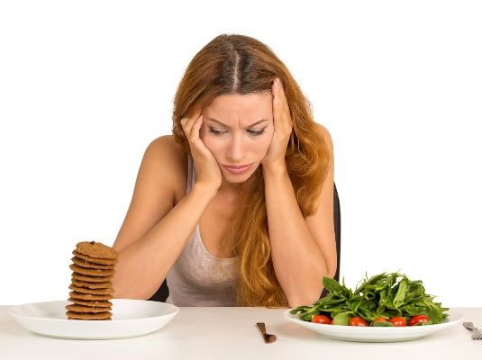 Young woman tired of diet restrictions deciding whether to eat healthy food