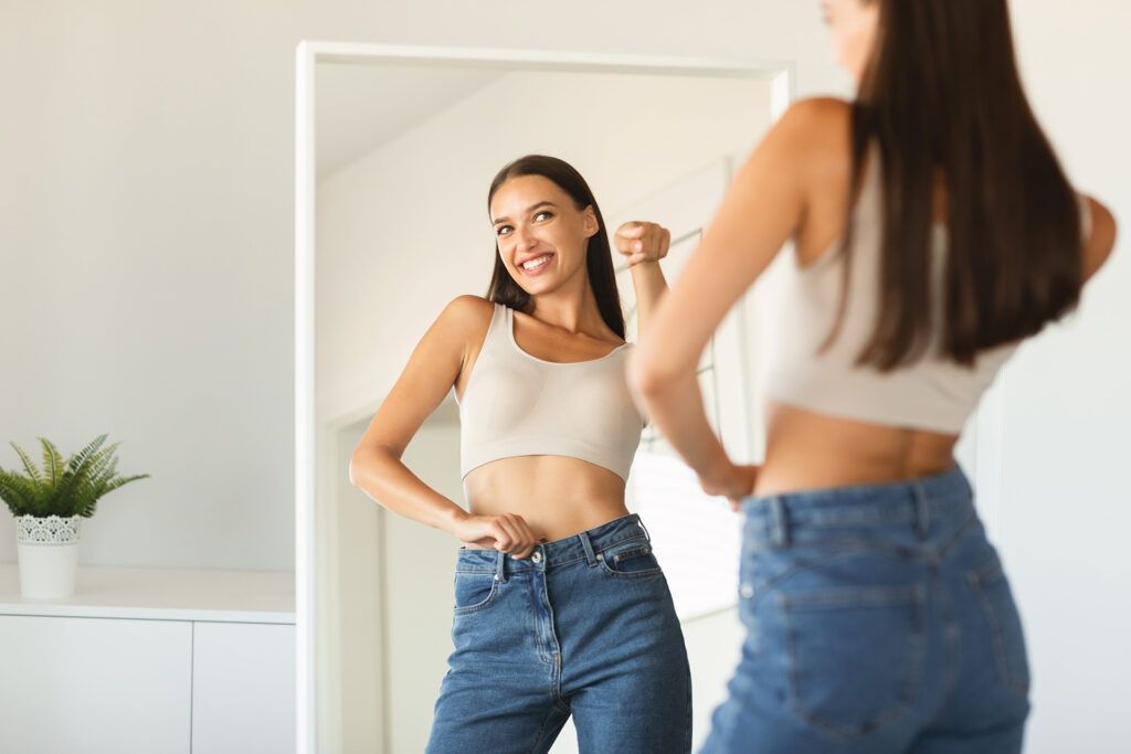 Happy lady pointing finger at her reflection in mirror