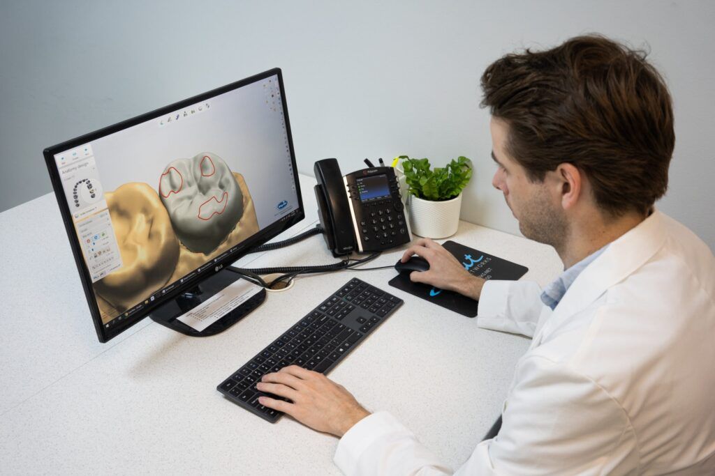 Male dentist working On Computer Screen In clinic