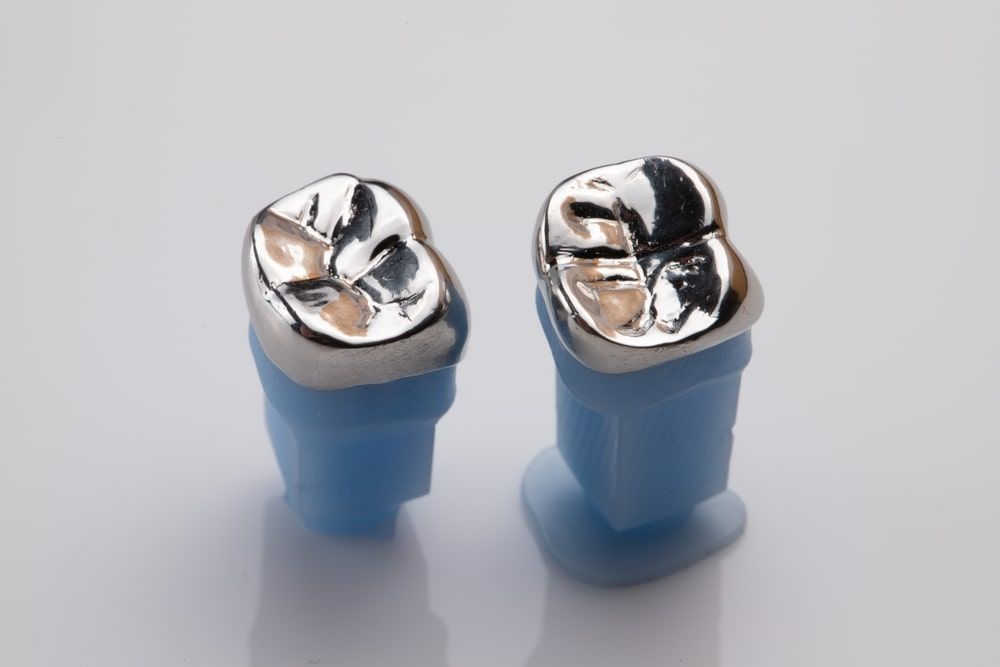 Metal dental crown place on blue plastic holder