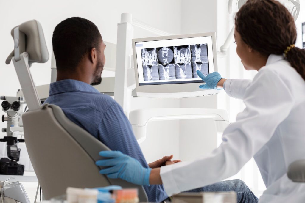 Female dentist and male patient watching x-ray on digital screen