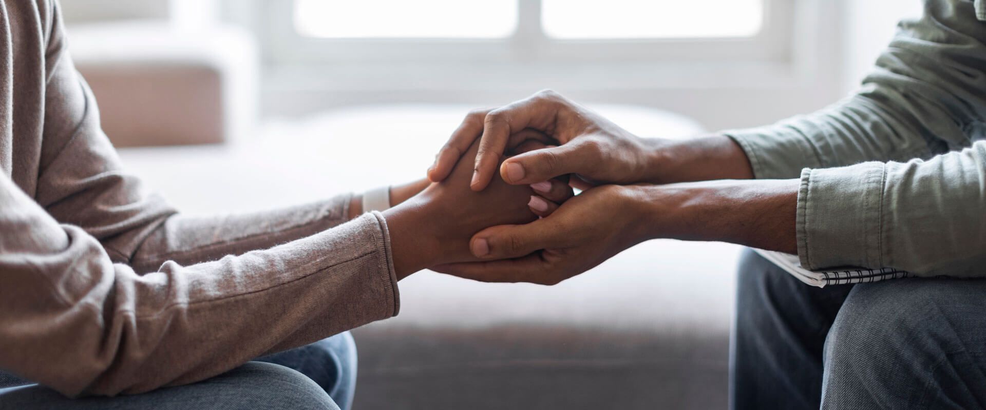 Man psychologist holding hands of woman patient