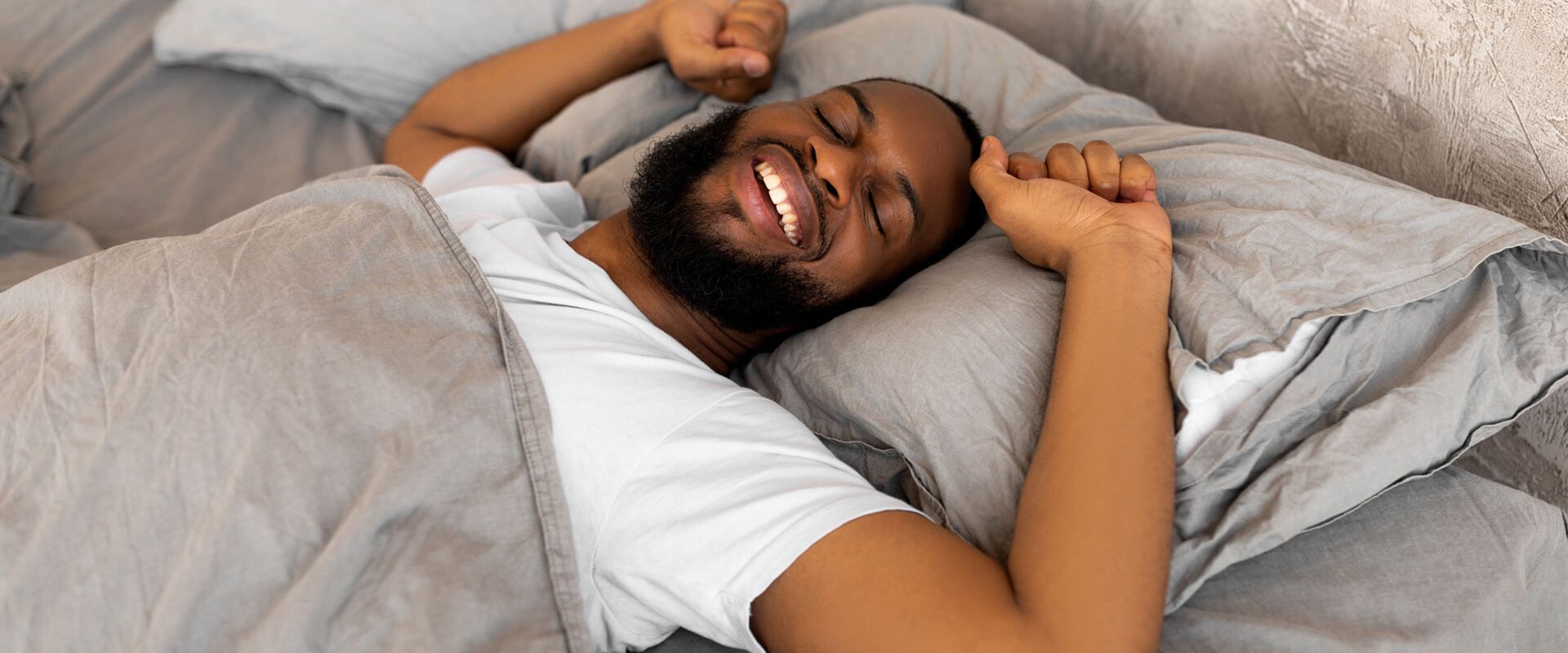 Satisfied young man stretching arms after wake up